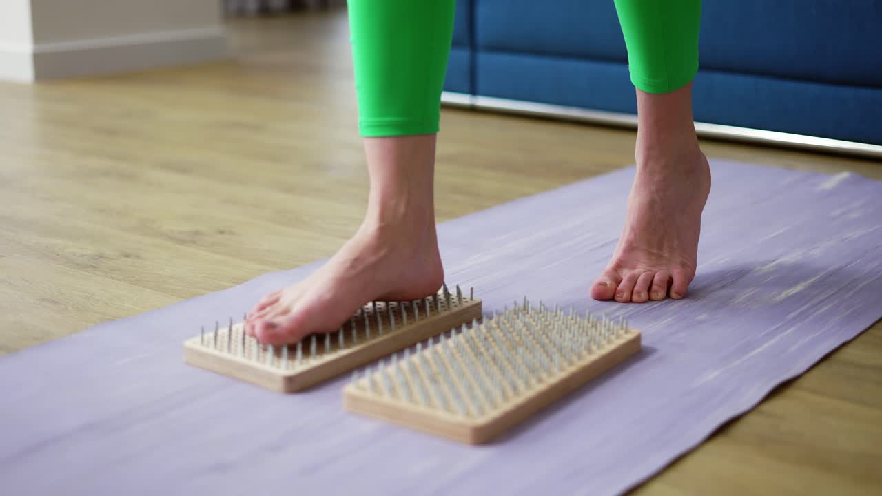 Close up of woman's feet stepping on sadhu board indoors at home