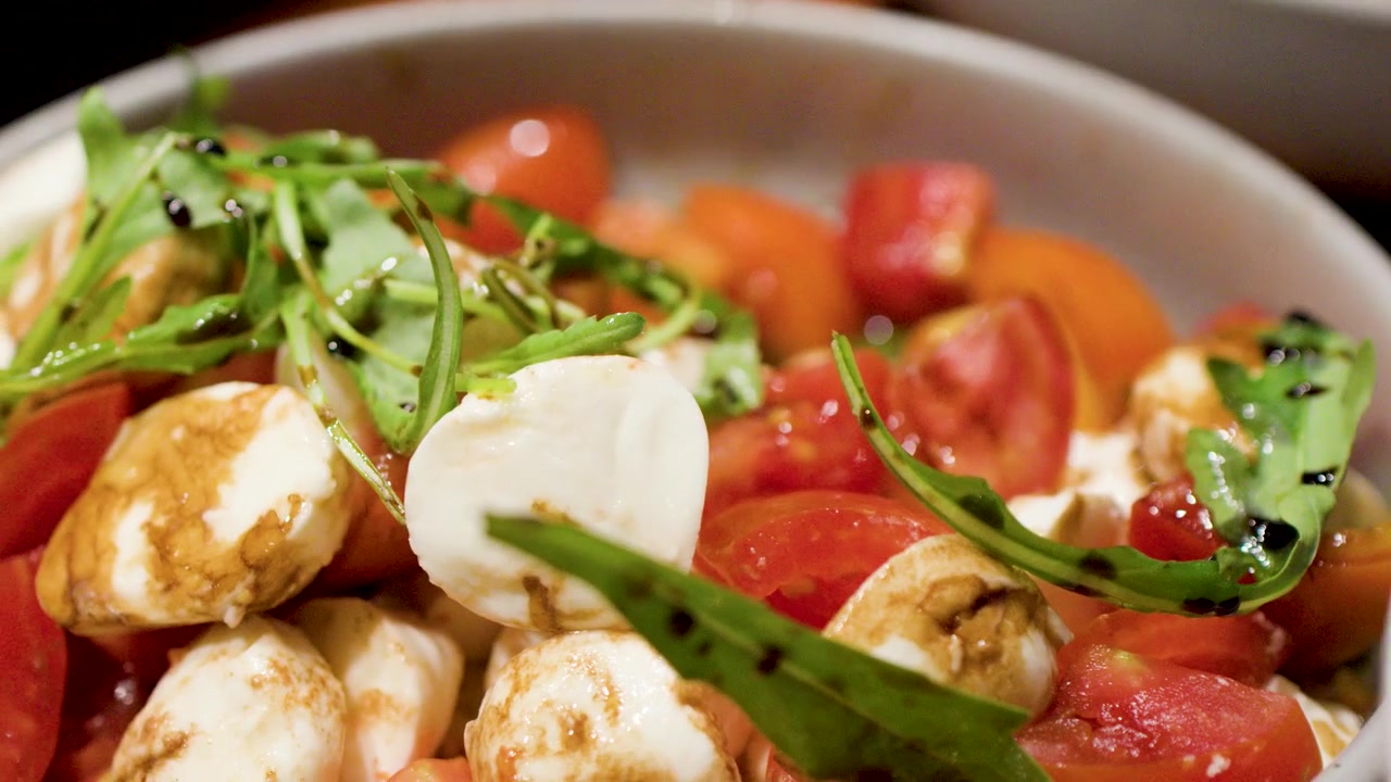 Primo piano di insalata Caprese fresca con glassa balsamica servita a un buffet internazionale.