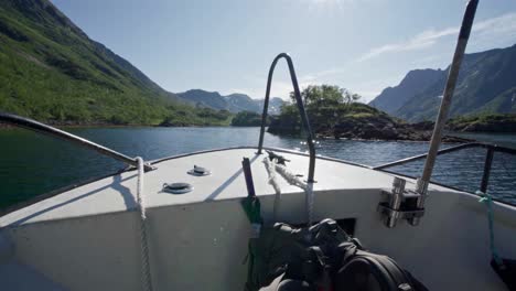 boat bow on quiet lake with mountainscape on background during sunny day in norway