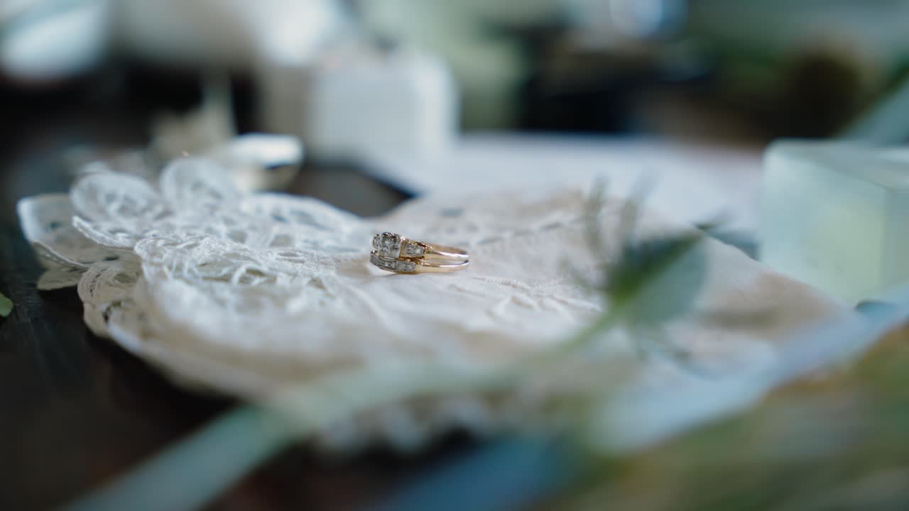 Close-up shot of a bride’s wedding ring resting on a lace cloth. Perfect for highlighting wedding details and bridal preparations.