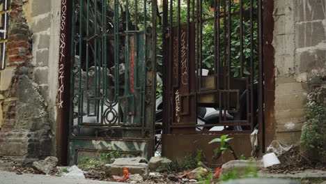 A-rusty-old-gate-with-graffiti-outside-a-derelict-and-abandoned-building-in-Colonia-Juárez,-Mexico-City