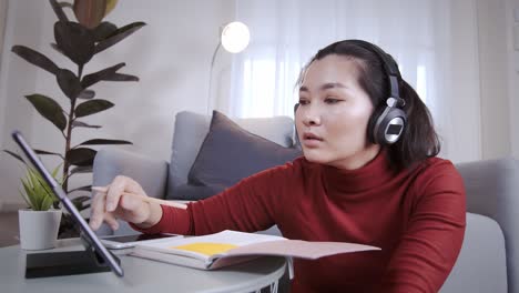 Freelance-woman-redshirt-using-tablet-with-headphone-for-meeting-online-at-home