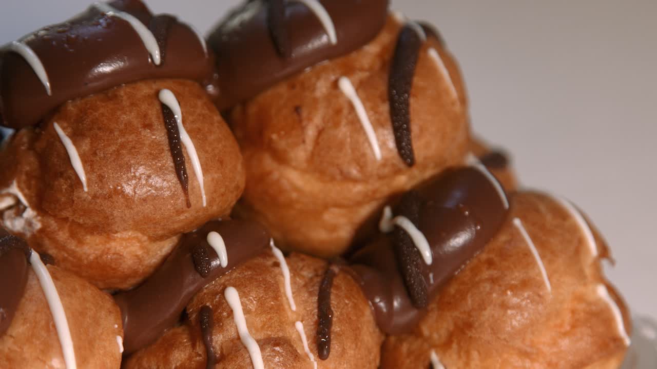 fotografía de cerca de profiteroles con relleno de crema batida y chocolate en la parte superior
