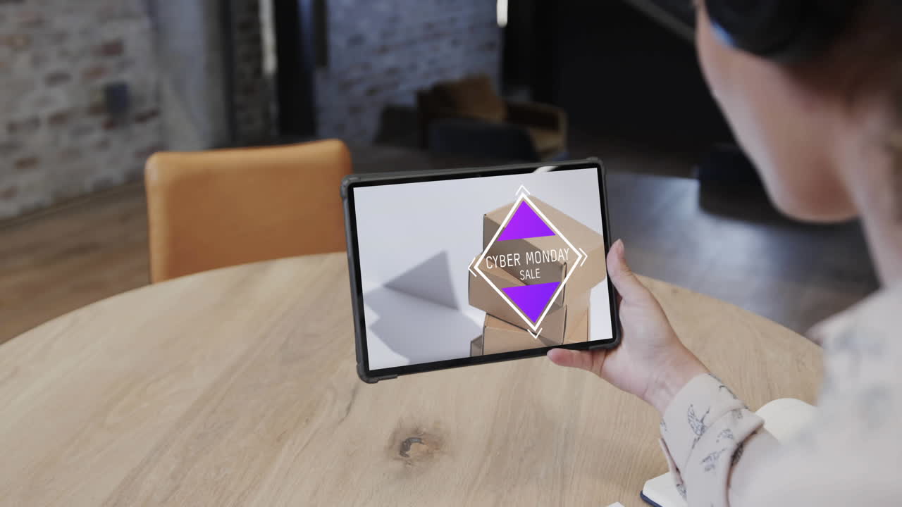 mujer biracial usando tableta en una cafetería comprando en línea en el día de venta del lunes cibernético, cámara lenta