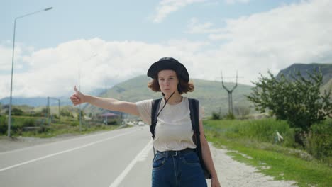 young woman hitchhiking on a mountain road