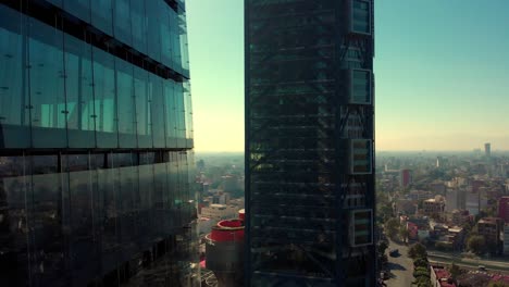 Drone-Volando-Hacia-Adelante-Al-Lado-De-Rascacielos-Ciudad-De-México-Luz-Del-Día-Cálido-Paisaje-Reflejos-Ventanas