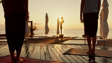 two guys watch the sunrise and meditate while standing. zen morning on sunny beach