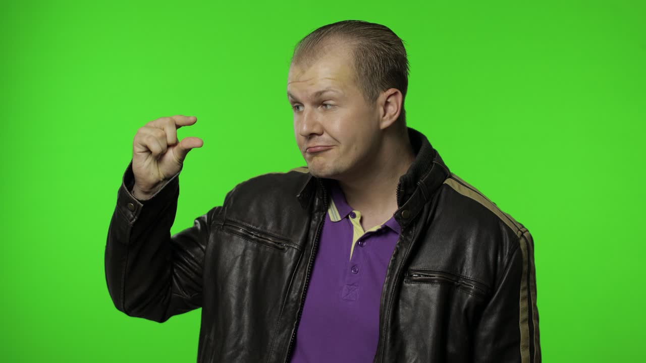 hombre mirando a la cámara mostrando un pequeño gesto, sintiéndose escéptico sobre el tamaño pequeño, la escala baja