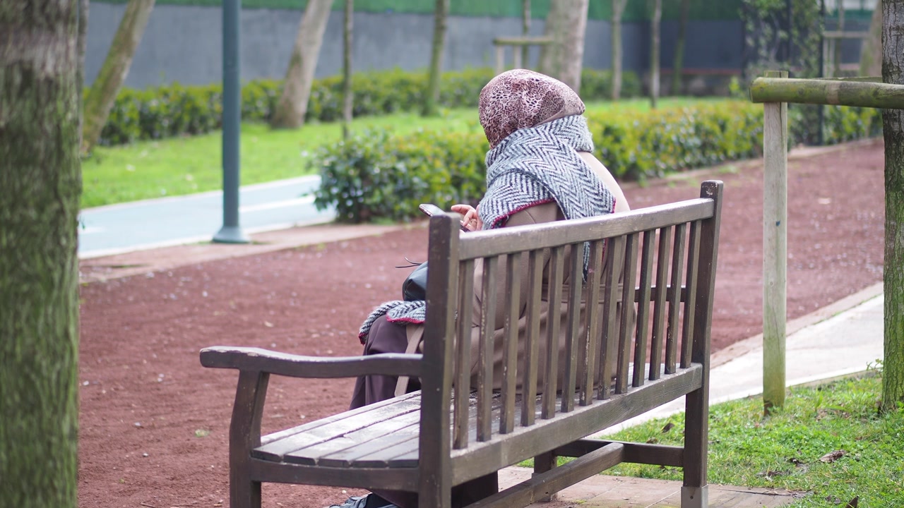 Woman Sitting on a Park Bench Using Her Mobile Phone