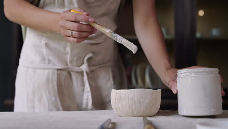 woman painting a ceramic bowl