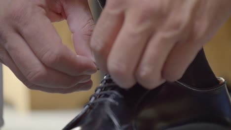 groom putting on black formal shiny shoes, preparing for wedding