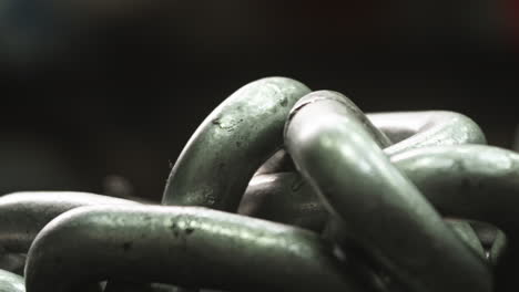 Heavy-metal-chains-on-floor-of-gym-weight-room,-Close-Up,-Pan-Right,-Slow-Motion