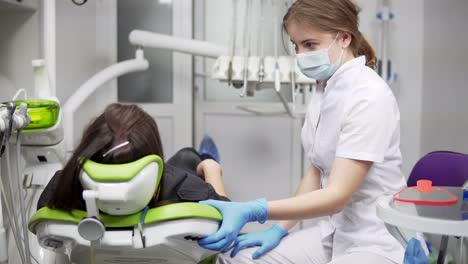 Der-Zahnarztstuhl-Erhebt-Sich-Mit-Dem-Patienten.-Junge-Zahnärztin-Drückt-Den-Knopf,-Um-Den-Behandlungsstuhl-Zusammen-Mit-Dem-Patienten-Anzuheben.