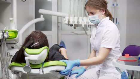 dentist chair raises up with patient. young female dentist pushes button to raise dental chair up with patient.