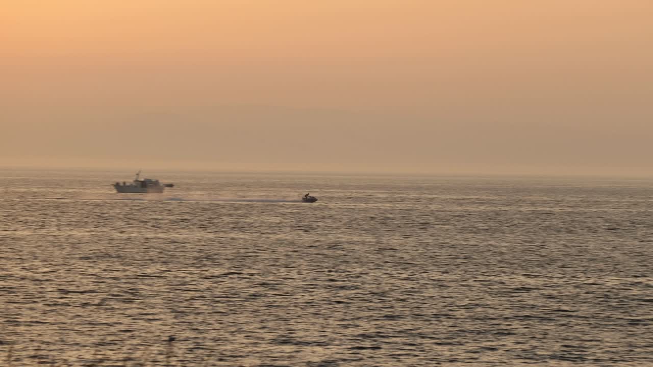 해가 지는 동안 아이르 해변에서 만을 가로지르는 제트 스키 선수의 트래킹  ⁇