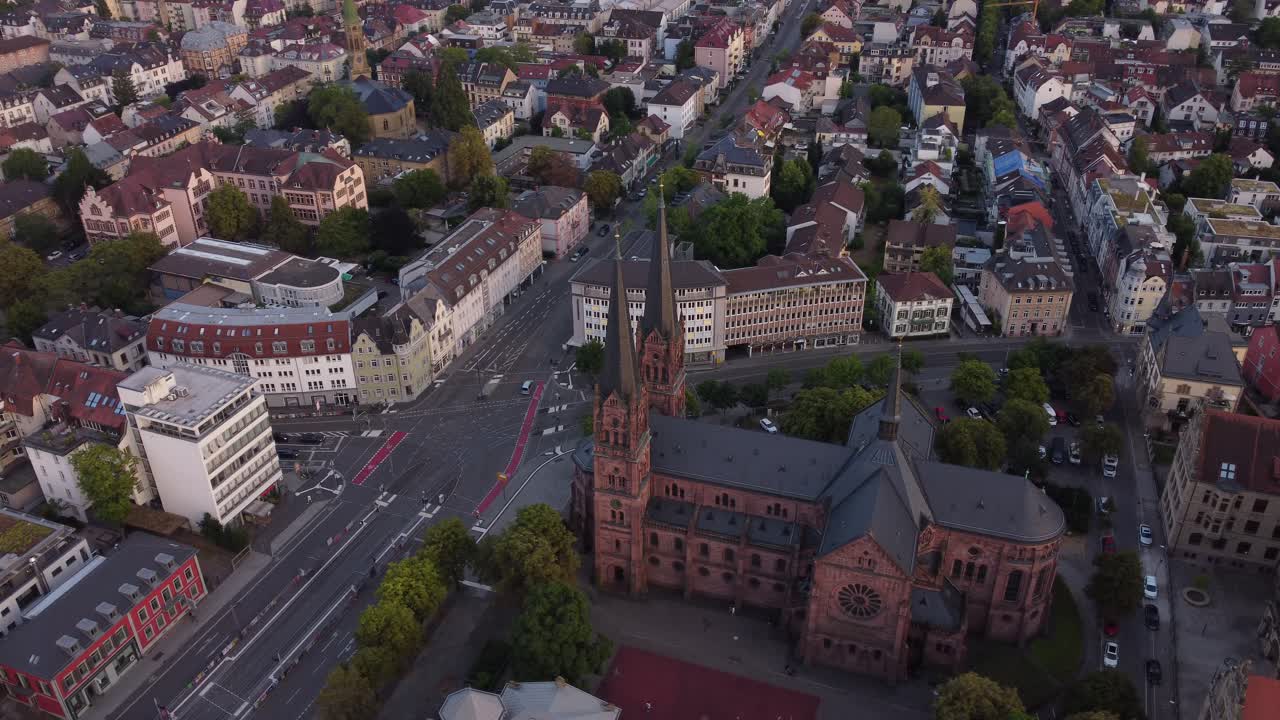 Drone circling around catholic church Johanneskirche and revealing scenic gothic old town of Freiburg im Breisgau during sunset, Germany