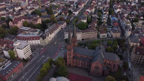 drone circling around catholic church johanneskirche and revealing scenic gothic old town of freiburg im breisgau during sunset, germany