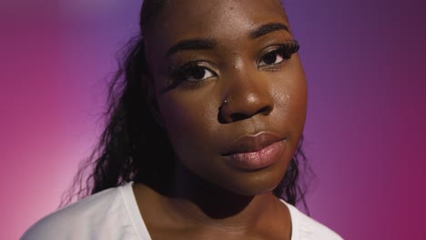 head and shoulders studio portrait of young woman against blue and pink lit background