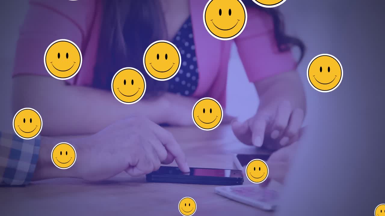 스마트 폰을 사용하는 사람들의 중간 부분에 대해 떠다니는 여러 개의 미소 얼굴 이모티콘