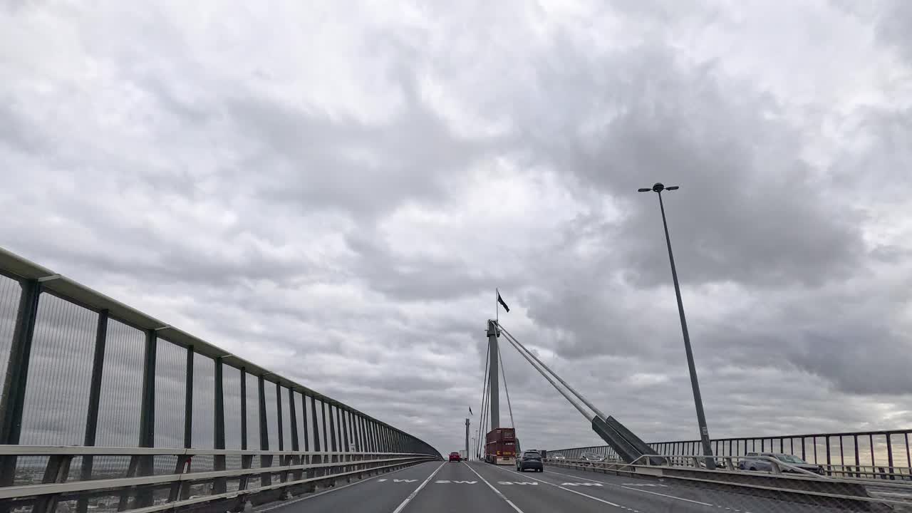 차가 구름이 가득한 하늘 아래 다리를 건너고 있다