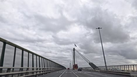 car crossing bridge under cloudy skies