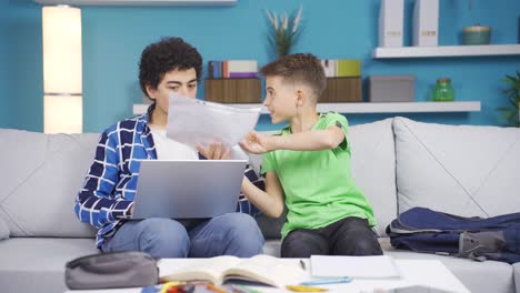 el hermano menor le muestra su informe escolar a su hermano mayor en casa.