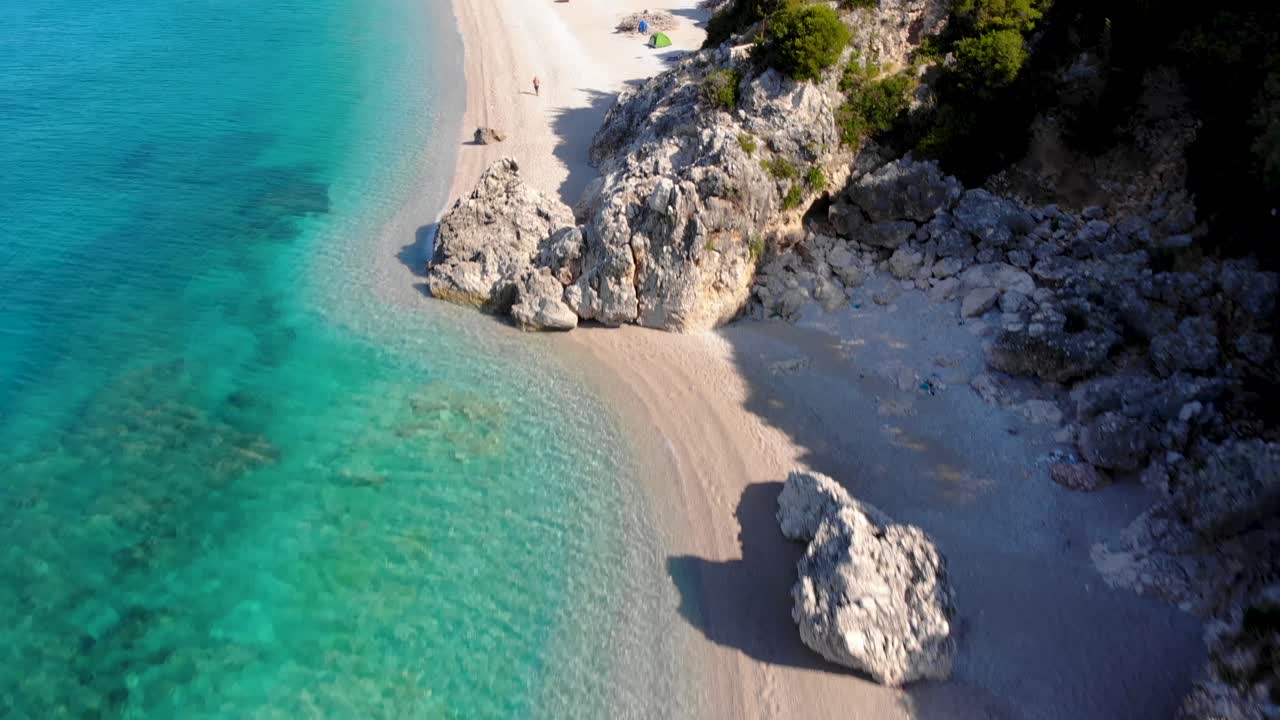 Sandstrande og klipper skyllet af krystalklart smaragdfarvet havvand på en smuk kystlinje i Middelhavet.