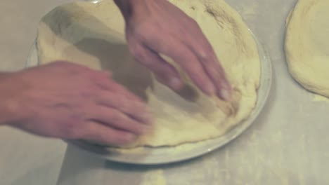 italian chef showing how to place the pizza dough on a place before the pizza dressing