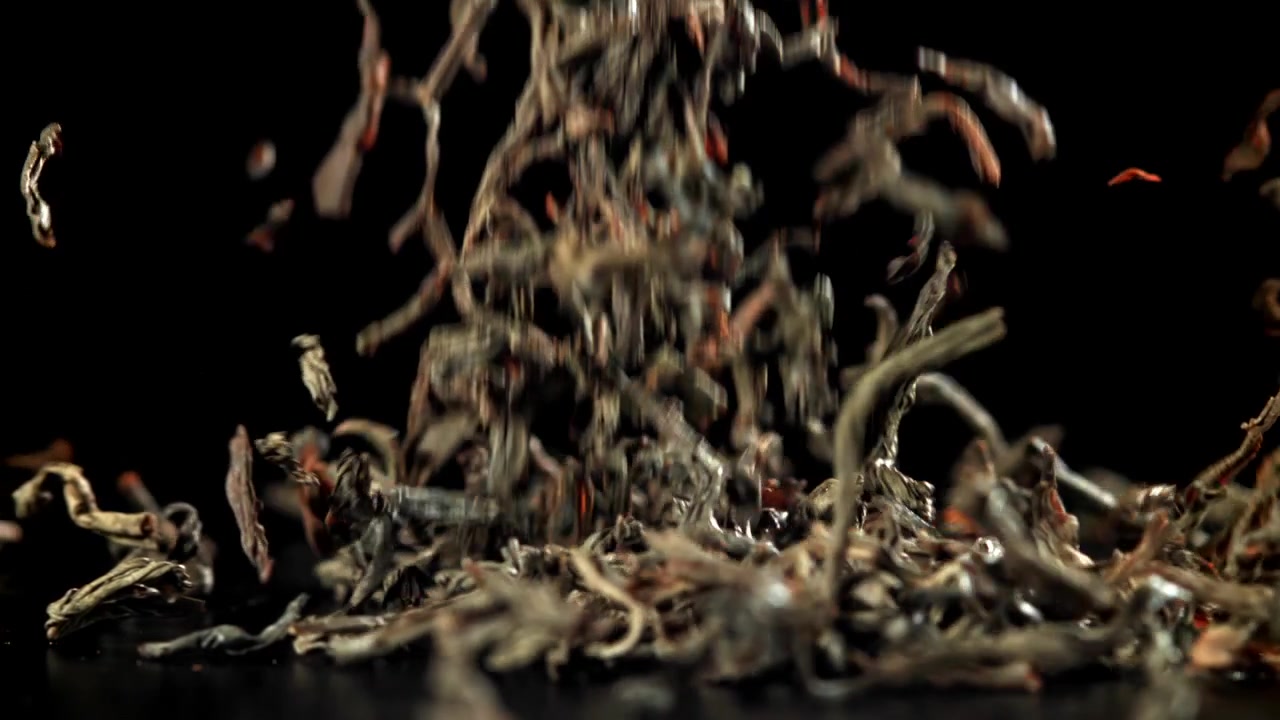 Dried Tea Leaves Falling in Slow Motion on Black Background