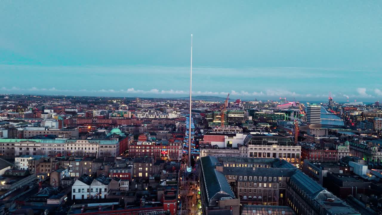 Luftaufnahme einer Drohne, die sich im Winter in der blauen Stunde der Dämmerung auf der irischen Stadtlandschaft einem Wahrzeichen in Dublin, Irland, nähert, mit beleuchteten Straßen mit Autos und TouristInnen, die unten hergehen