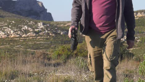 Man-holding-binoculuars-in-wilderness-walking-towards-camera