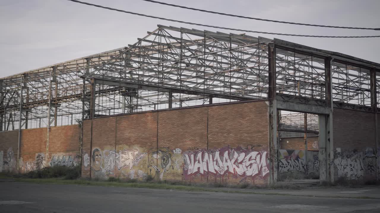 Abandoned warehouse - Panoramic shot from the outside with murals on the wall at sunset