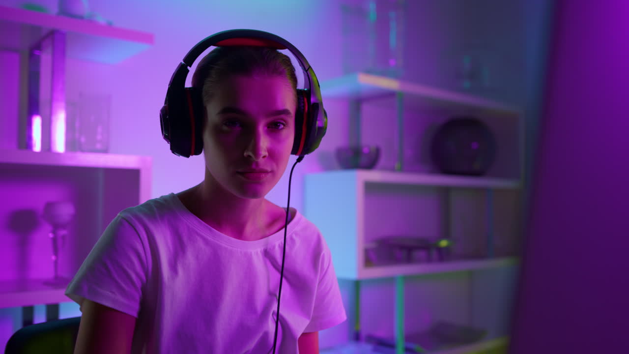 Primo piano di bella ragazza gamer in luci al neon a casa. Professionista eSport concentrata