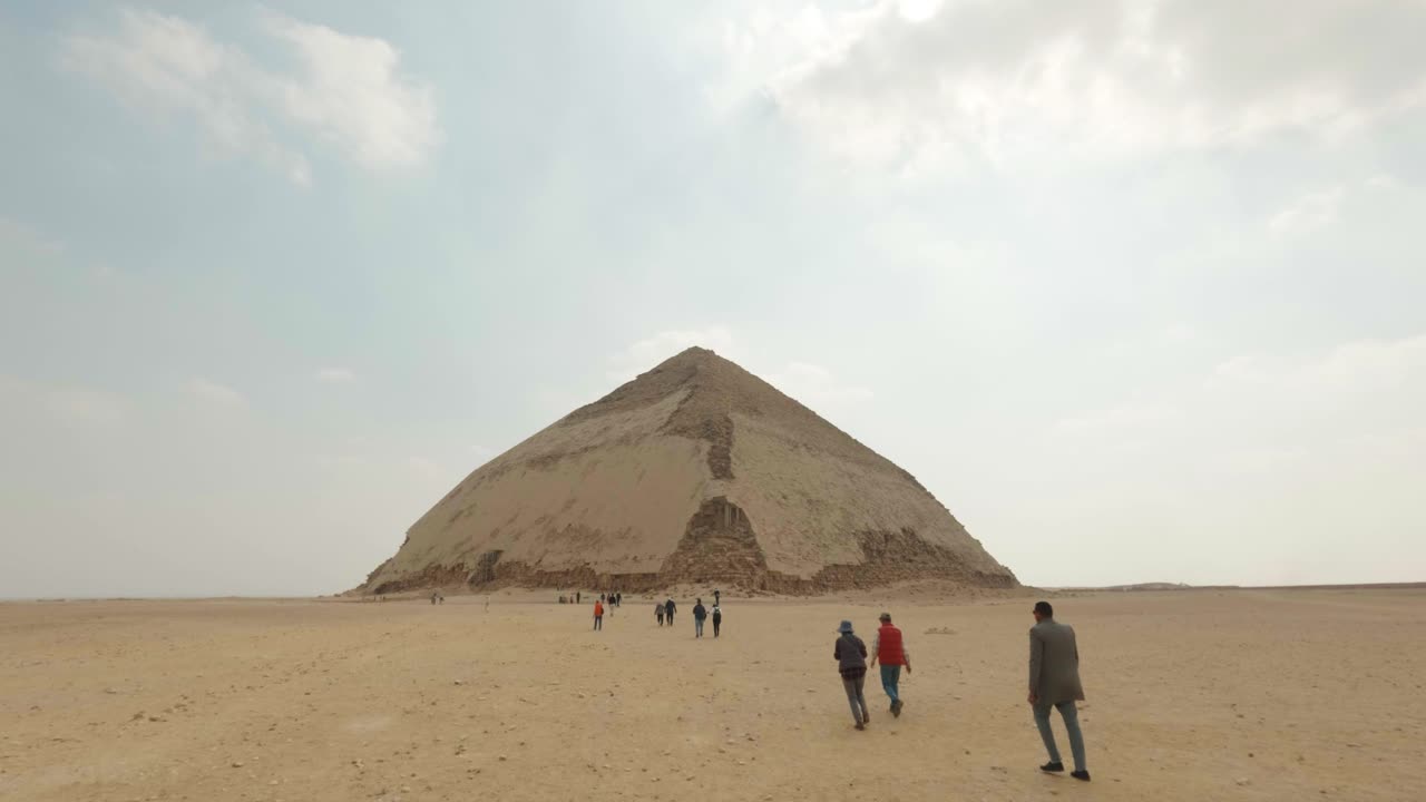 Lidé kráčející směrem k starověké Lomené pyramidě v Dahšúru v Egyptě