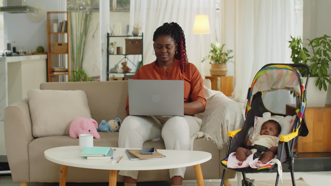 Mother of Newborn Baby Working on Laptop at Home