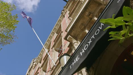 A-Purple-Flag-Waving-At-The-Facade-Of-The-Hoxton,-Amsterdam-In-Herengracht,-Amsterdam,-Netherlands