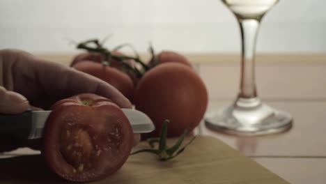 Hands-chopping-fresh-vine-tomatoes-on-chopping-board-close-up-shot