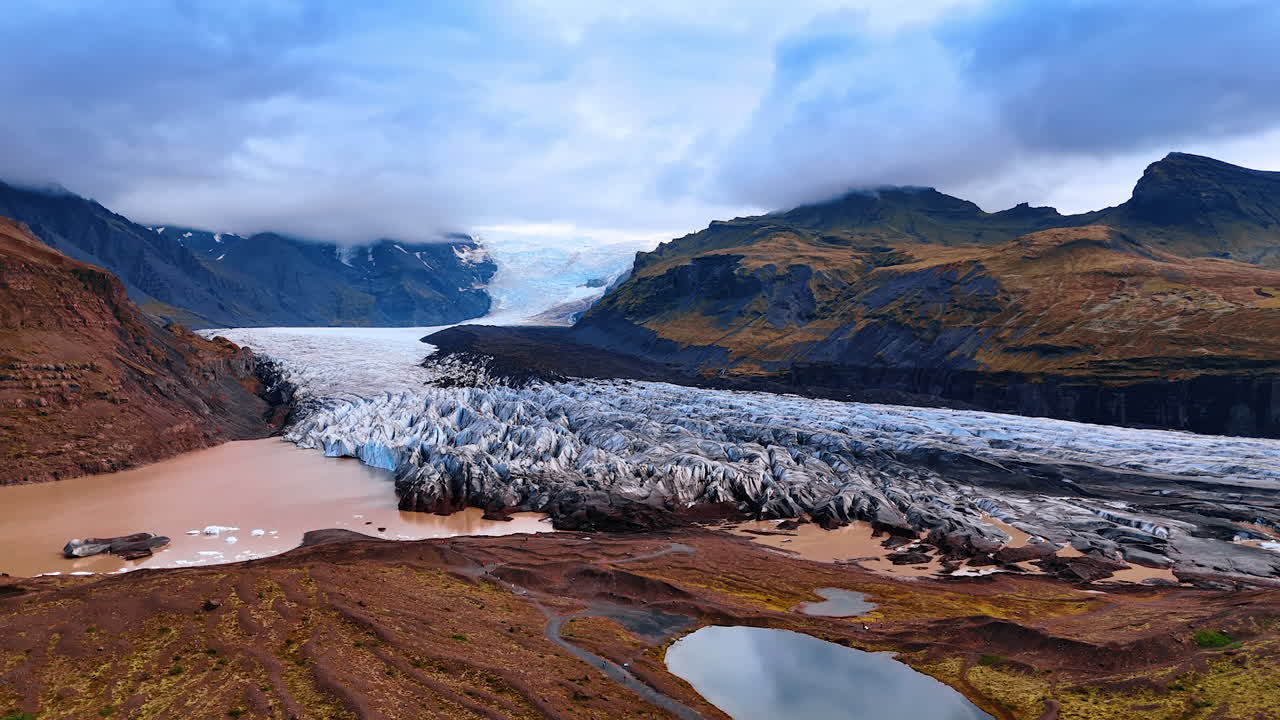 Iceberg ranges among the mighty mountains. Heavy cloudscape covering the mountain tops. Unreal landscape of Iceland.