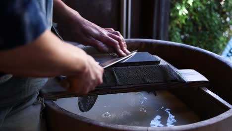 person meticulously sharpening a knife blade