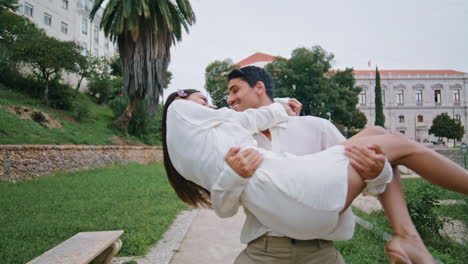 excited lovers rejoicing in garden. latina man carrying laughing woman at hands