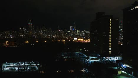 Aerial---Push-In-Towards-City-Skyline-with-Subway-Train-Approaching-at-Night