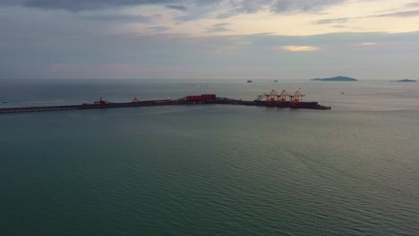 Sobrevuelo-De-Drones-Aéreos-Estrechos-De-Malaca,-Mar-En-La-Costa-Oeste-De-Malasia-Capturando-El-Muelle-De-Exportación-De-La-Corporación-Minera-De-Mineral-De-Hierro-Del-Valle-Brasileño,-Embarcadero-De-La-Terminal-Logística-A-Granel-A-Lo-Largo-Del-Horizonte-Al-Atardecer