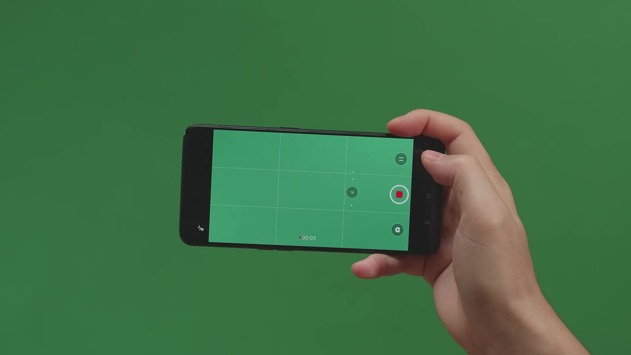 Hands Holding Cell Phone And Recording Video With Green Screen In Green Background