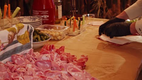 el chef decora la mesa con porciones de carne de jamón de parma por la noche