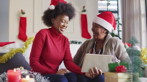 Feliz-Madre-Afroamericana-E-Hija-Adulta-Con-Sombreros-De-Santa-En-Videollamada-Navideña,-Cámara-Lenta