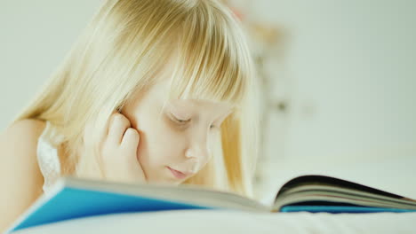 niña rubia leyendo un libro en la cama 4k video 27