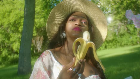 black woman calmly eating banana in park close up pan