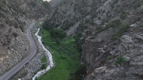 Revelando-Hermosas-Tomas-De-Drones-De-Un-Pequeño-Valle-Con-Una-Carretera-Junto-Al-Río-Y-Campos:-El-Hermoso-Valle-De-Chilas,-Pakistán