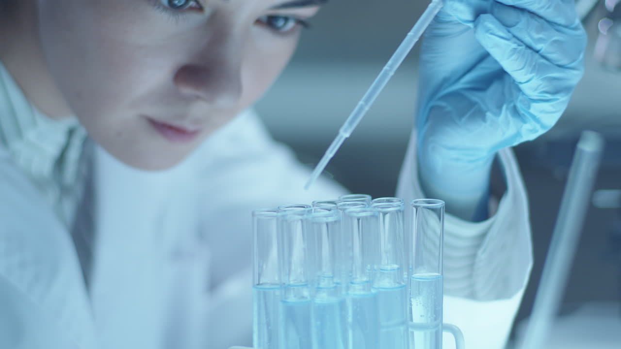 Medical Microbiologist Pouring Liquid Chemicals in Test Tubes with Pipette
