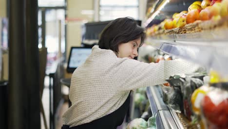 woman with down syndrome restocking fresh fruits in a grocery store